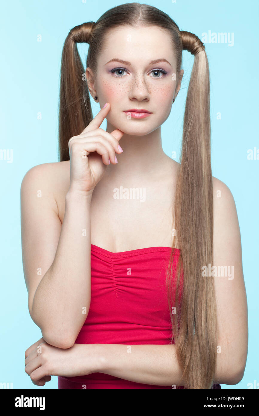 Schönen verspielten sommersprossiges Mädchen im roten Kleid auf blauem Hintergrund Stockfoto