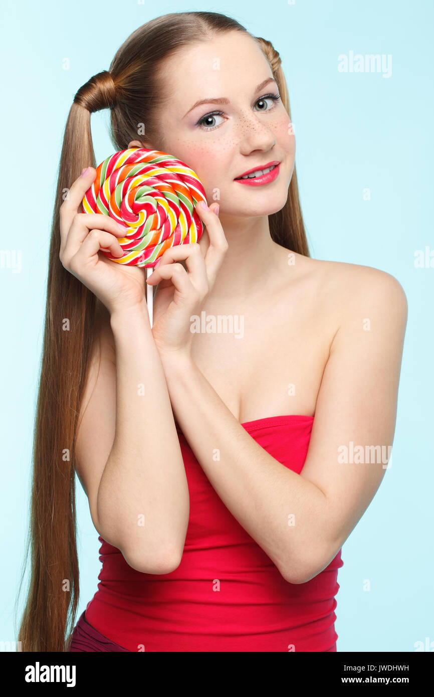 Wunderschöne verspielte junge sommersprossiges Mädchen mit Lollipop auf blauem Hintergrund Stockfoto