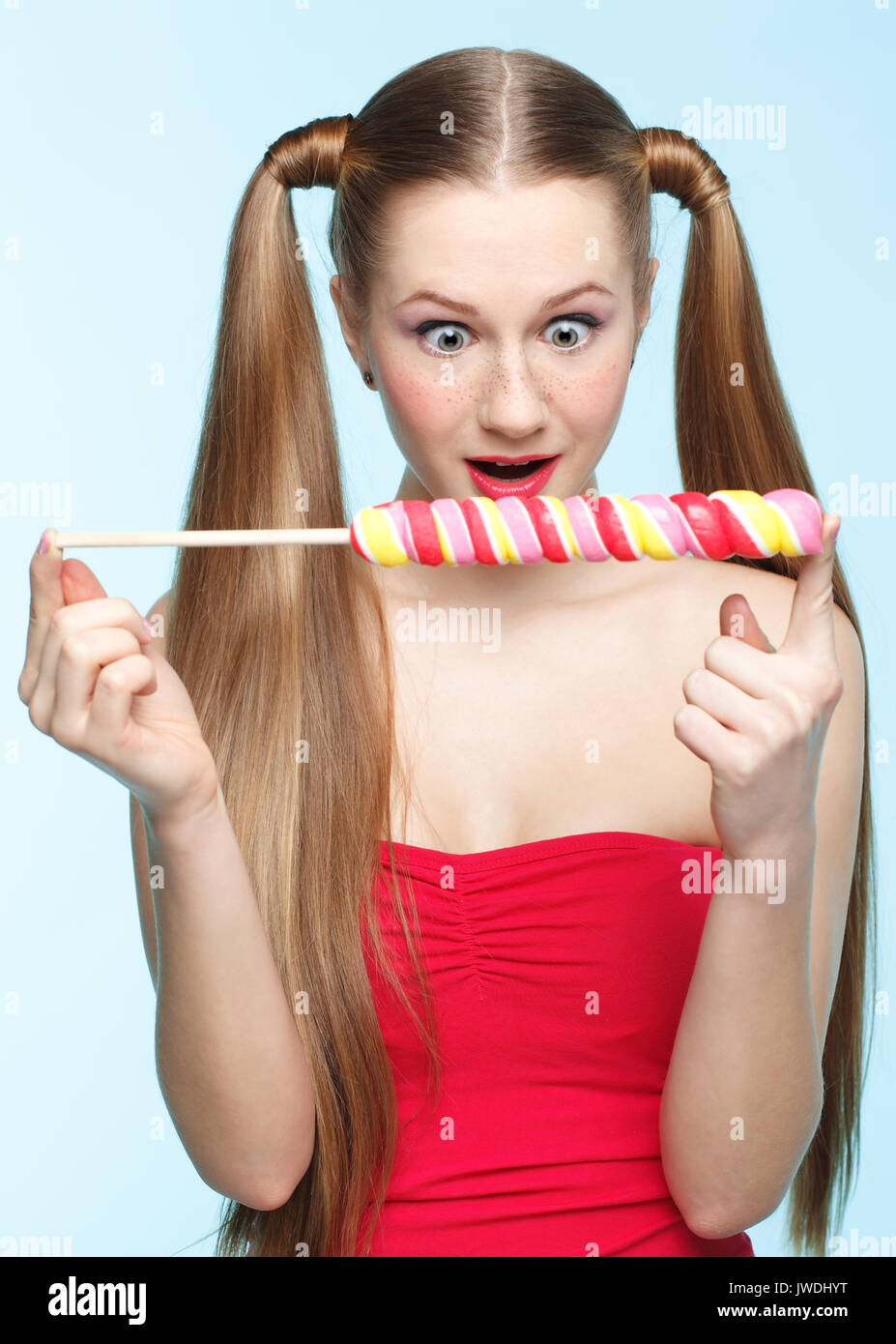 Wunderschöne verspielte junge sommersprossiges Mädchen mit Lollipop auf blauem Hintergrund Stockfoto