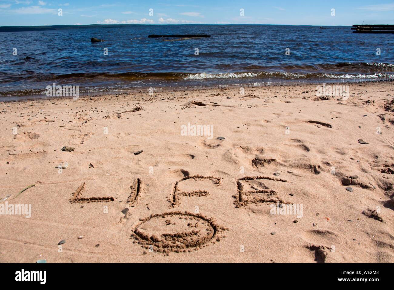 Die Inschrift am Ufer des Sees in den Sand, gegen den blauen Himmel und Wasser. Stockfoto