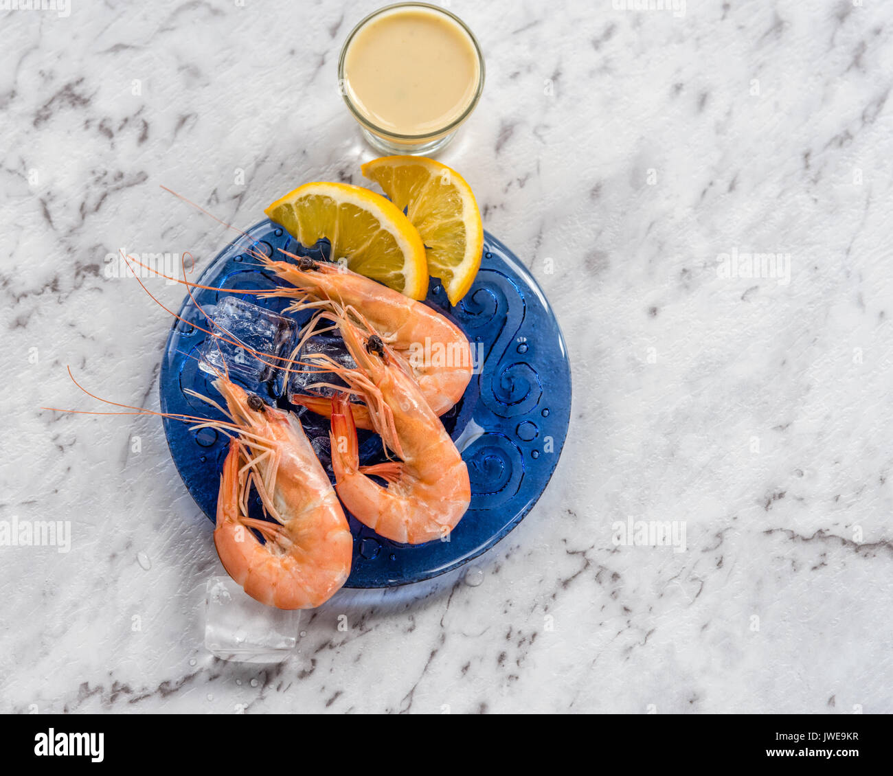 Garnele auf blaue Platte mit Soße weißer Marmor Hintergrund. Auf blaue Platte mit Sauce, Eis, Zitronenscheiben Prawn, weißem Marmor Hintergrund. Stockfoto