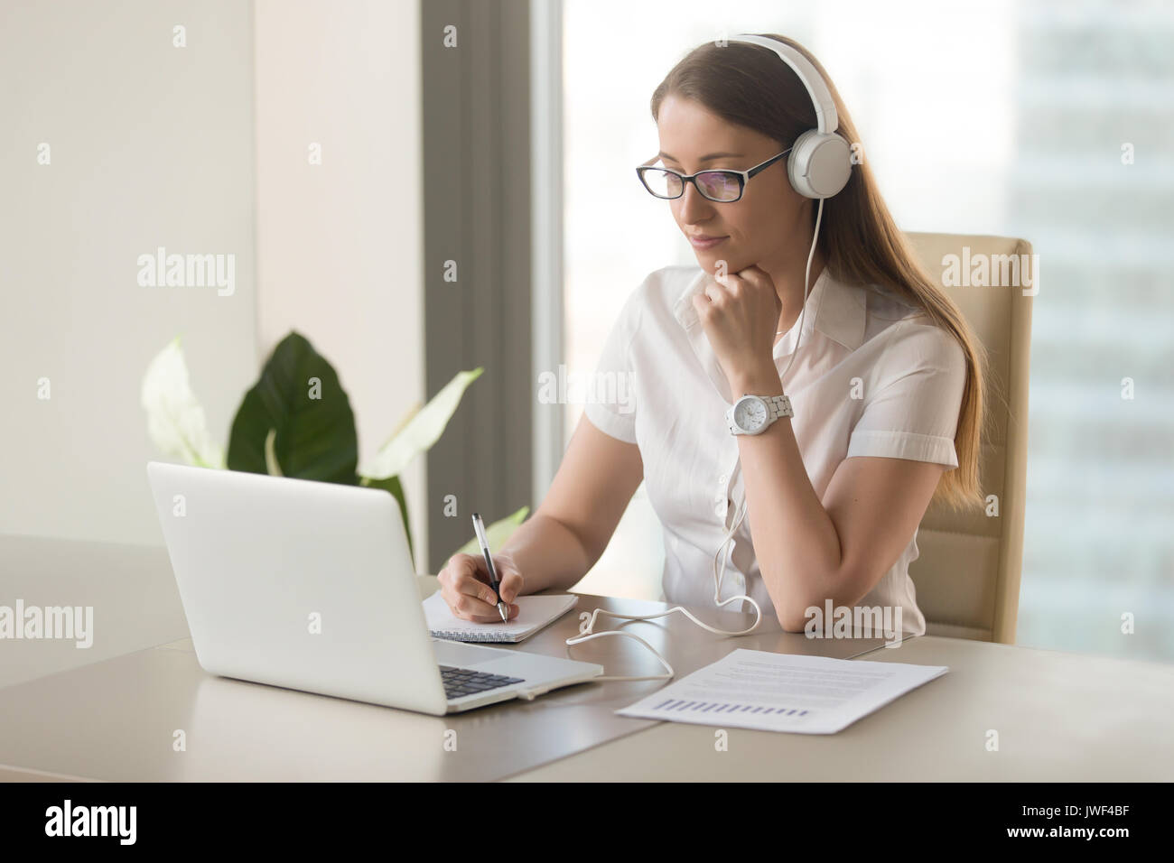 Aufmerksame Frau das Tragen von Kopfhörern mit Laptop auf offic konzentriert Stockfoto