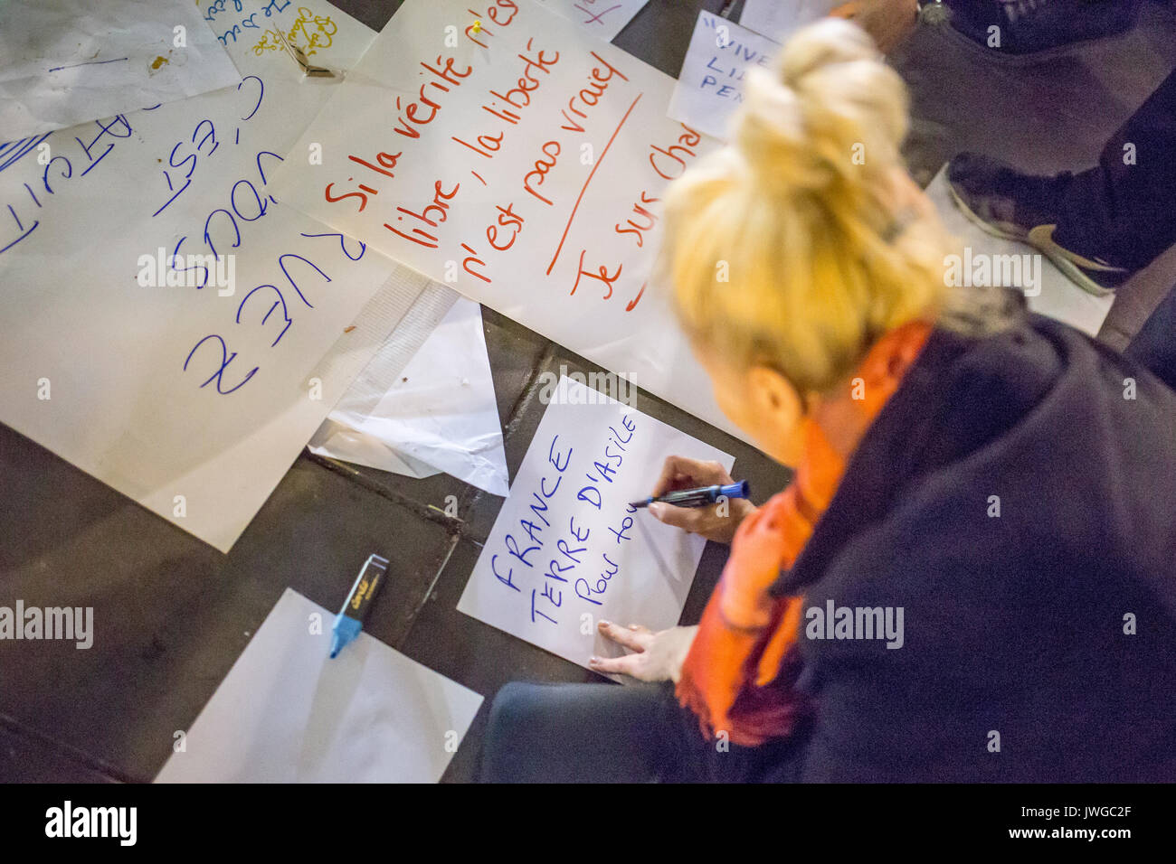 Hommage an die Opfer von Charlie Hebdo, eine Frau schreiben ein Zeichen: Frankreich Zuflucht und Asyl für alle, Terre d'asile Pour Tous Stockfoto