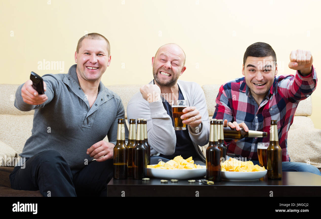 Drei männlichen Freunden am Tisch sitzen mit Bier und beobachten Sport TV-Kanal Stockfoto