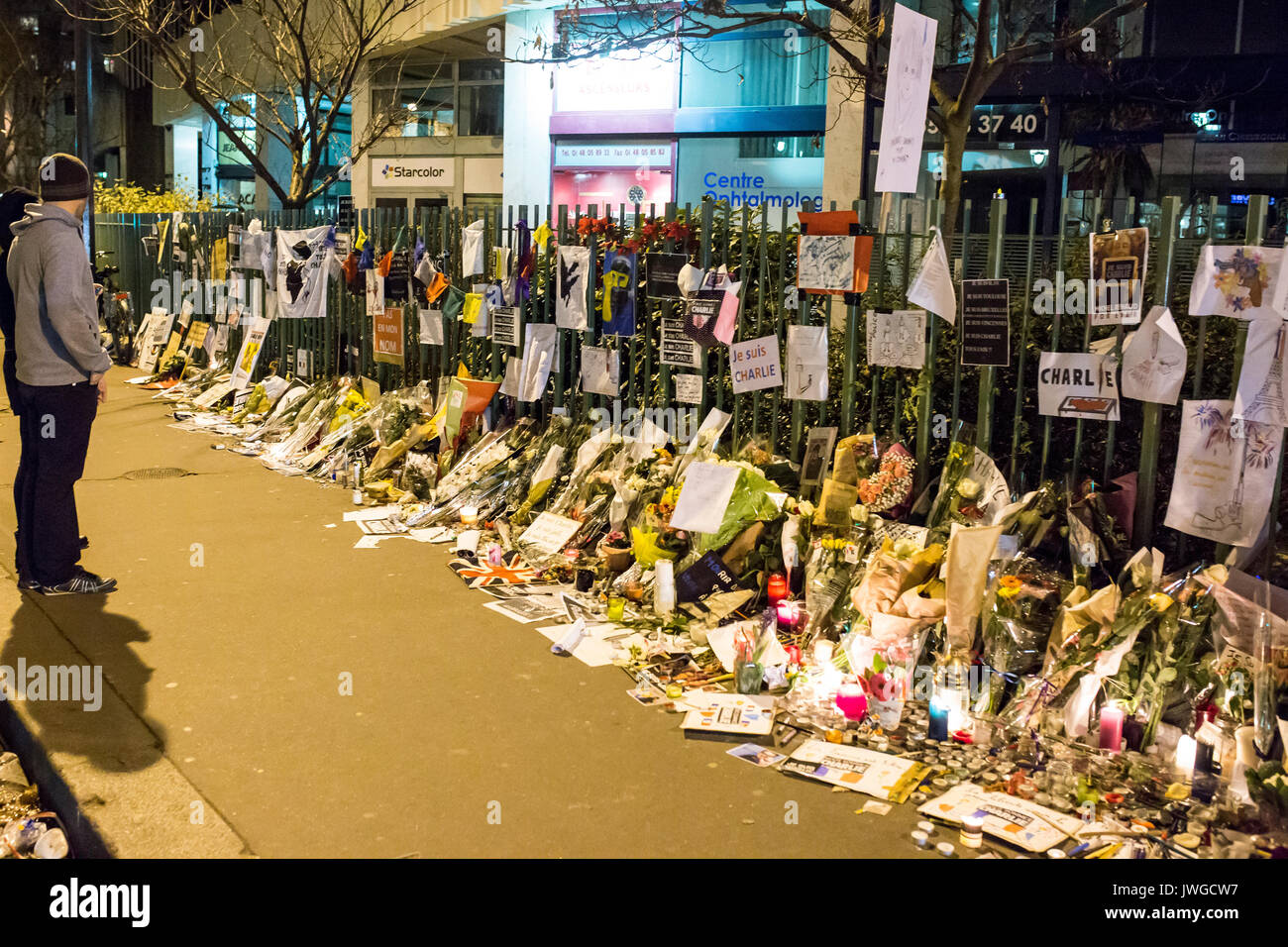 2 Personen am Zaun voller commemortaions, Zeichnungen, Notizen, Blumen suchen. Hommage an die Opfer von Charlie Hebdo Tötung in Paris das 7. von Jan Stockfoto