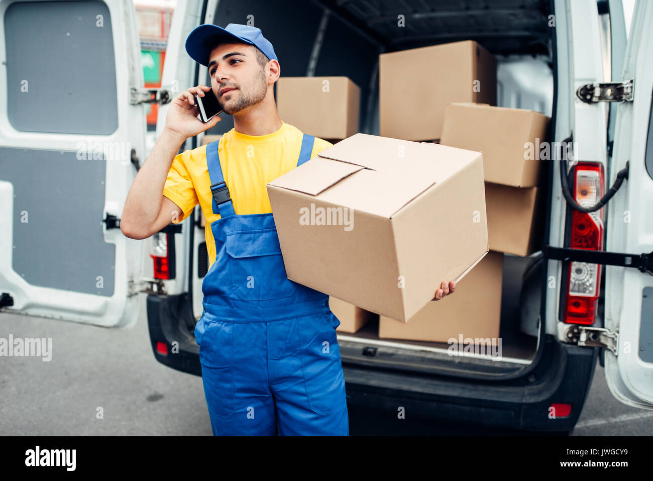 Cargo Lieferservice, männlichen Kurier in Uniform mit Box und Handy in den Händen. Leerer Behälter Stockfoto