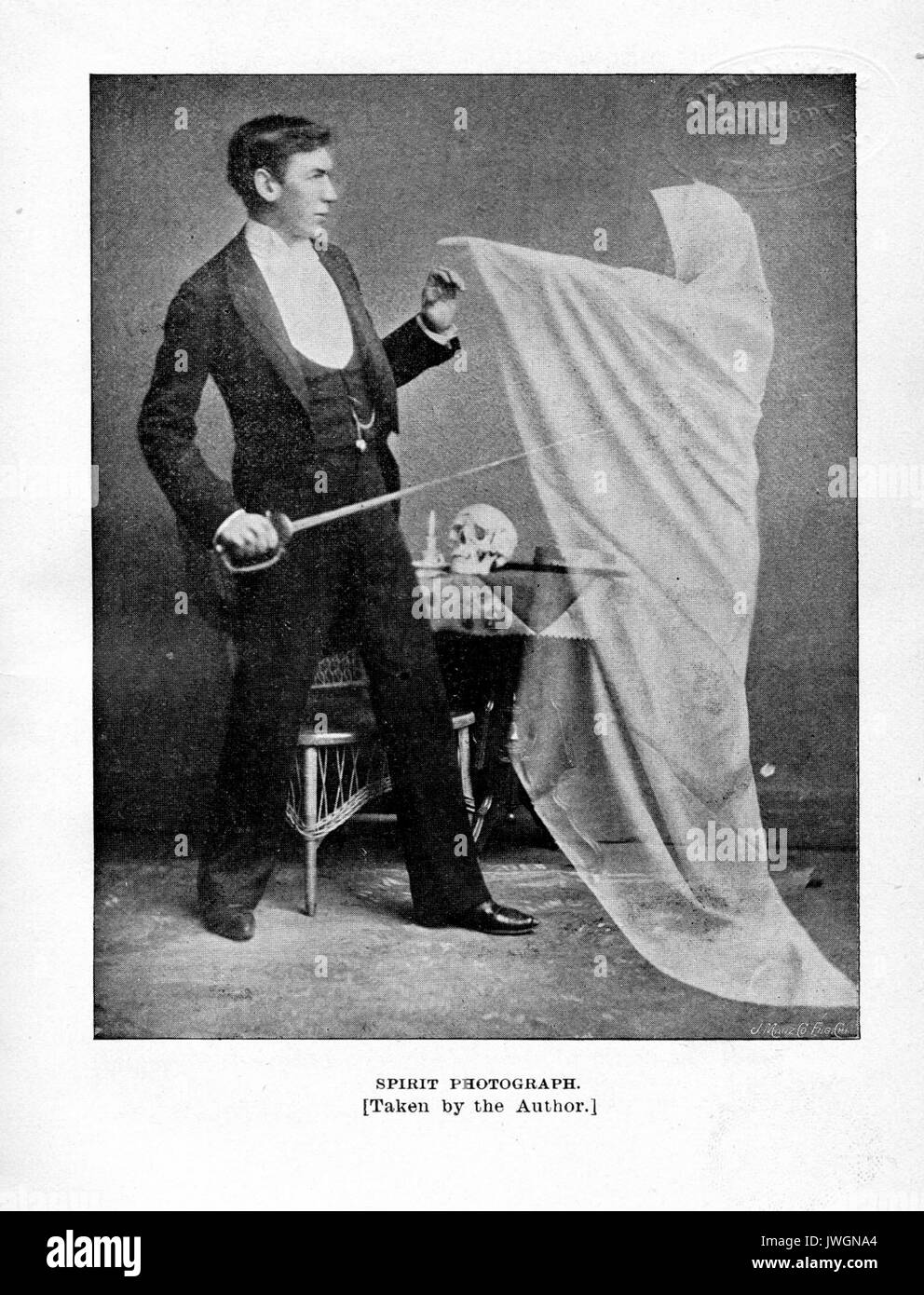 Geist Foto, Mann im Anzug mit einem Säbel und erreicht seine Hand die Hand eines Geistes in einen weißen Umhang, der über den Boden, Schädel und andere okkulte Gegenstände auf einem Tisch hinter dem Mann schwebt zu berühren, mit Bildunterschrift Lesung durch den Autor, 1893 übernommen. Stockfoto