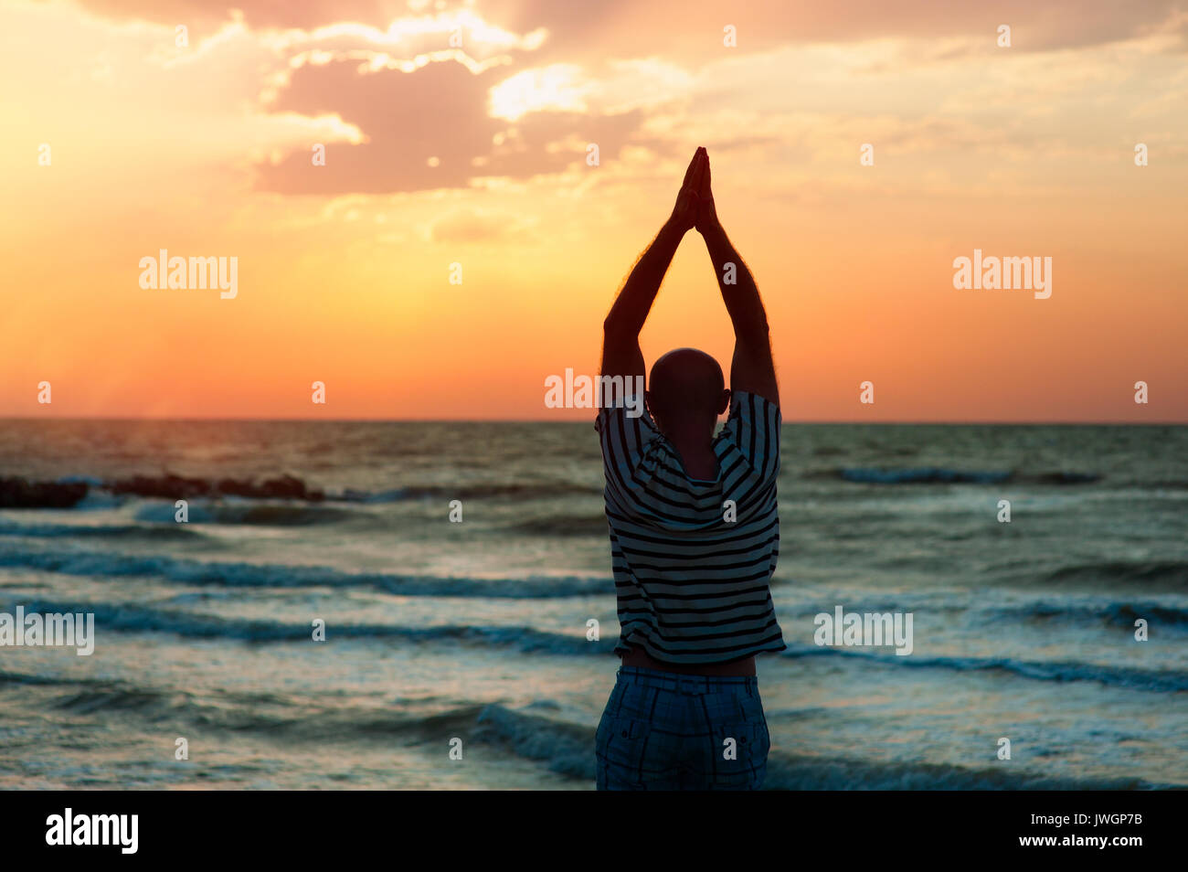 Die Silhouette eines Mannes, Yoga bei Sonnenuntergang am Strand Stockfoto