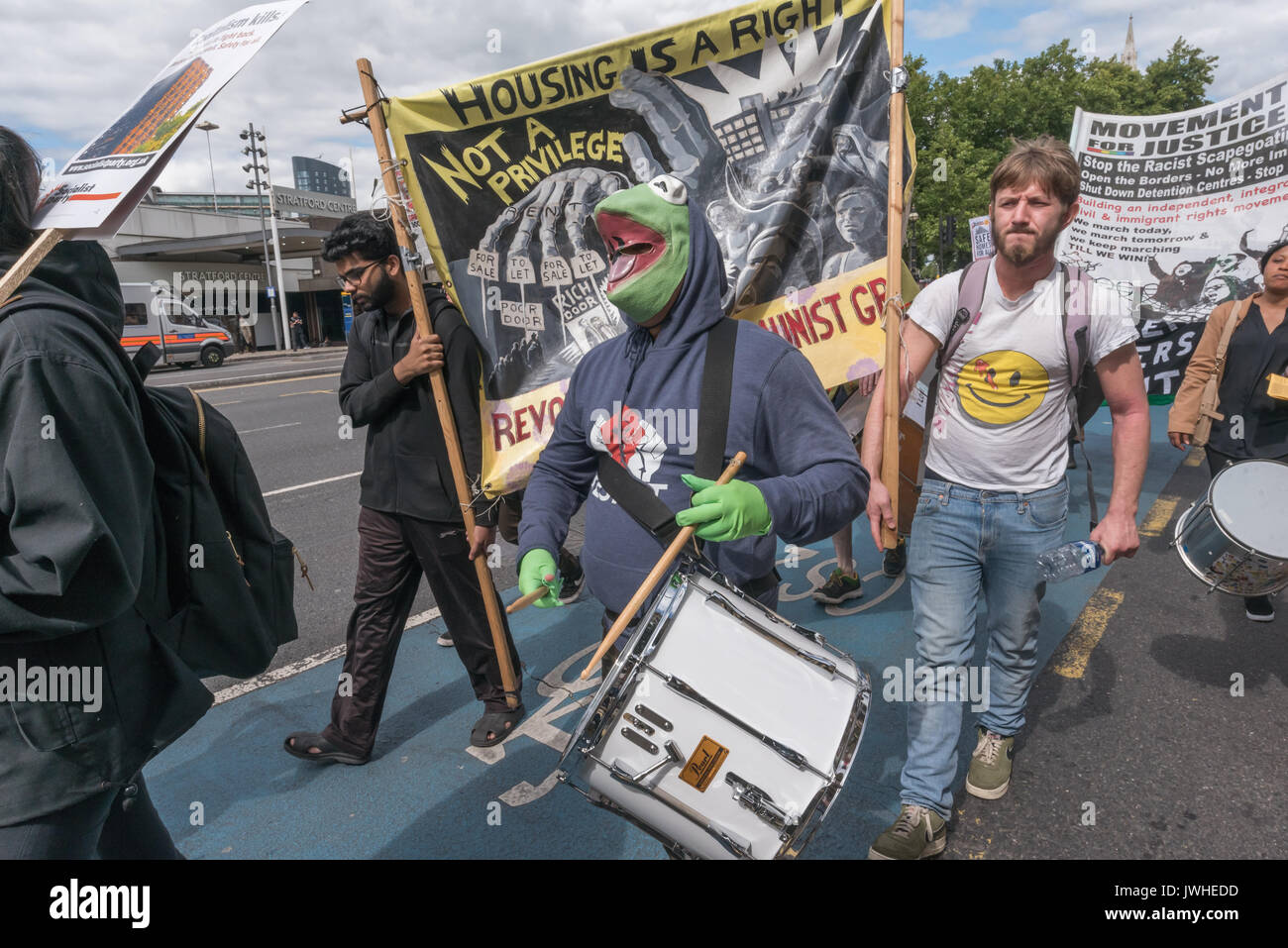 London, Großbritannien. 12. August 2017. Ein Schlagzeuger in einen Frosch costuem auf dem Marsch von Focus E 15 Mütter von Ferrier Punkt in Canning Town führte zu einer Kundgebung an Tanner Punkt in Plaistow weisen auf die Gefahr der beiden Bausteine mit den gleichen Mantel als Grenfell Tower, anspruchsvolle sichere Wohnungen, nicht soziale Säuberungen in East London. Sie setzte dann den Zimmerleuten Immobilien in Stratford weitgehend von Menschen über 10 Jahren geleert und will zu demolieren, für einen 'Hände um Solidarität bei den Zimmerleuten Immobilien" gegen Dekantieren, Credit: Peter Marschall/Alamy leben Nachrichten Stockfoto