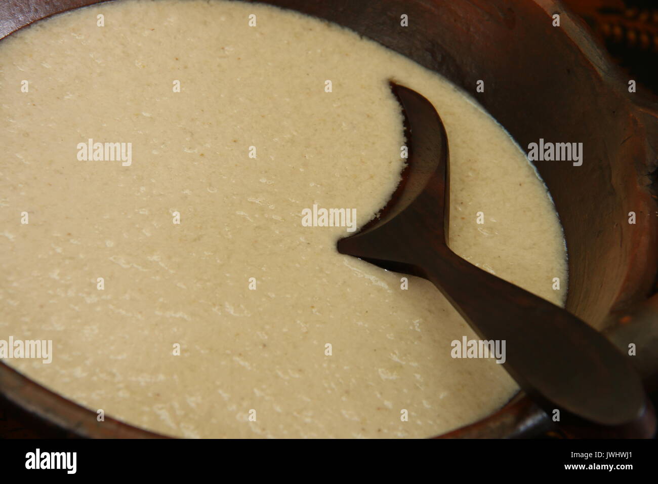 Santan Areh. Herzhafte Soße von Coconut Creme für Nasi Liwet Solo. In einem traditionellen Steingut Wok mit einem hölzernen Löffel serviert. Stockfoto