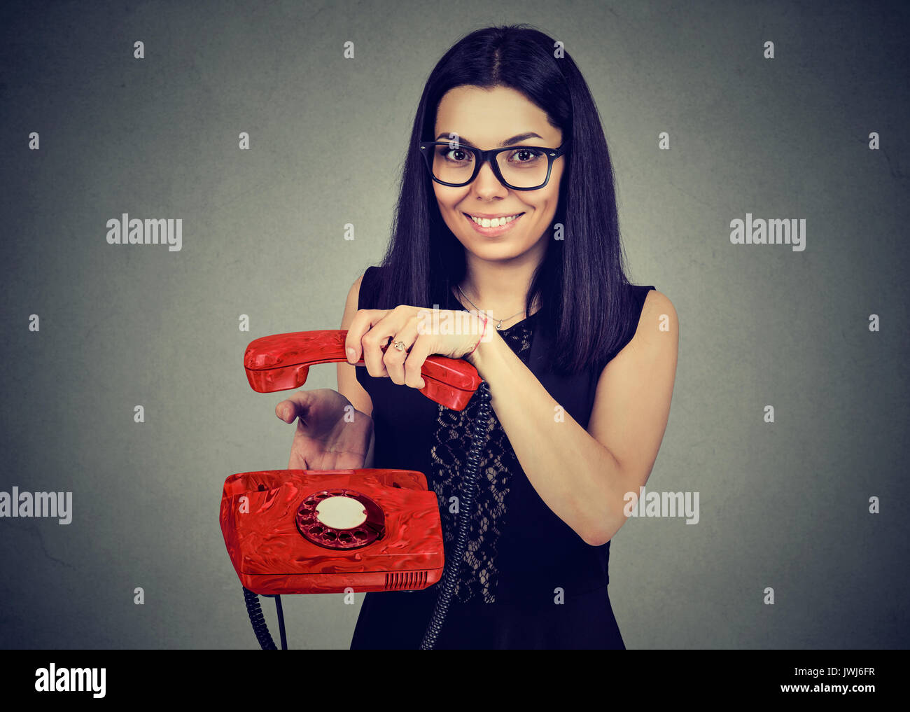 Lächelnde Frau zum Aufhängen von einem alten Telefon Stockfoto