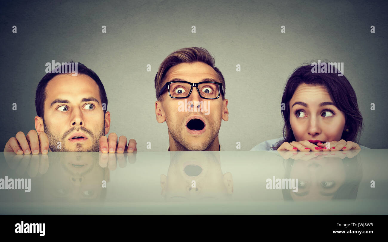 Junge Leute, zwei Männer und eine Frau verstecken peeking Form unter der Tabelle Angst Stockfoto