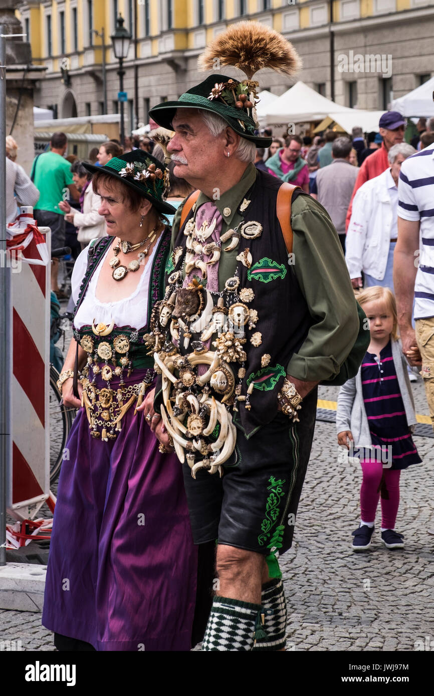 Typisch Bayerische Zeichen in der traditionellen Tracht der Lederhosen, Westen, Hüte mit Federn, Blumen, Emaille Namensschilder, Knochen Schmuck, und Männer disp Stockfoto