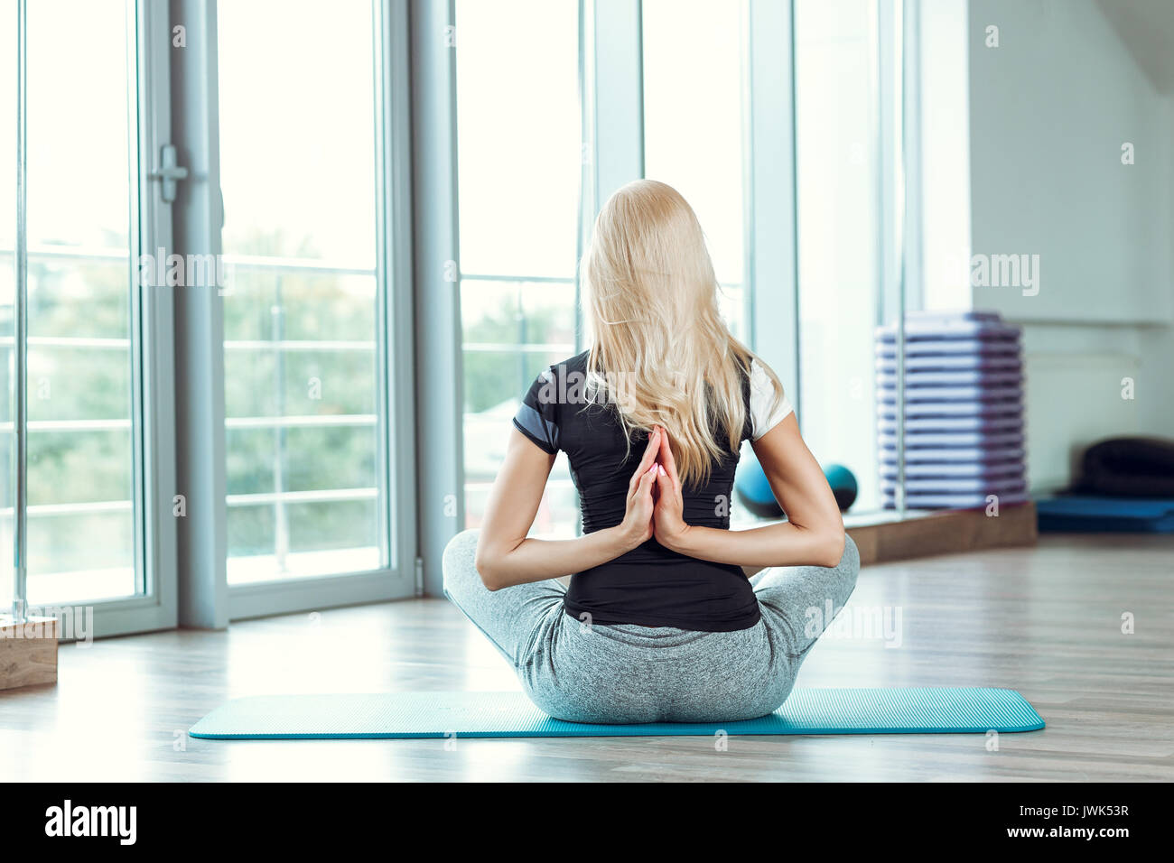 Junge Frau mit Yoga im Fitnessstudio. Mädchen Hände hinter ihrem Rücken verbinden Stockfoto