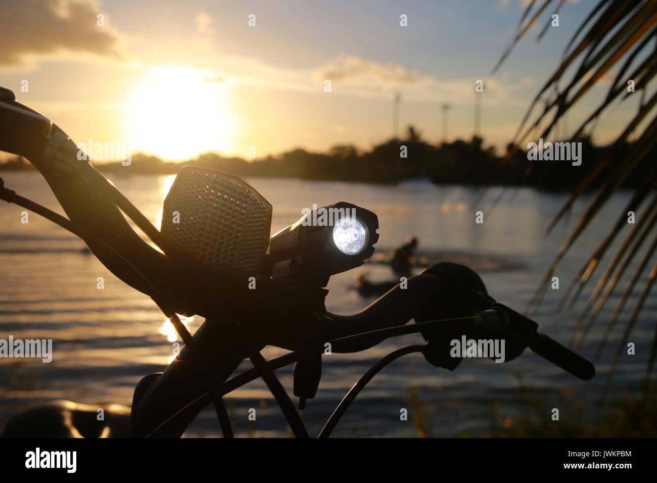 Fahrrad Licht beleuchtet auf Lenker gegen Sonnenuntergang auf See Stockfoto