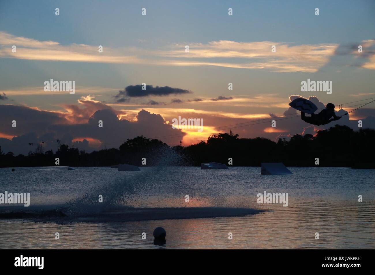 Wake Boarder auf der See bei Sonnenuntergang und hinter einer Wolke aus Wassernebel Stockfoto
