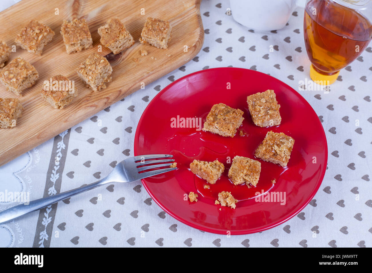 Frisch gebackene golden braun flapjacks in Ahornsirup auf rotem Blech abgedeckt Stockfoto