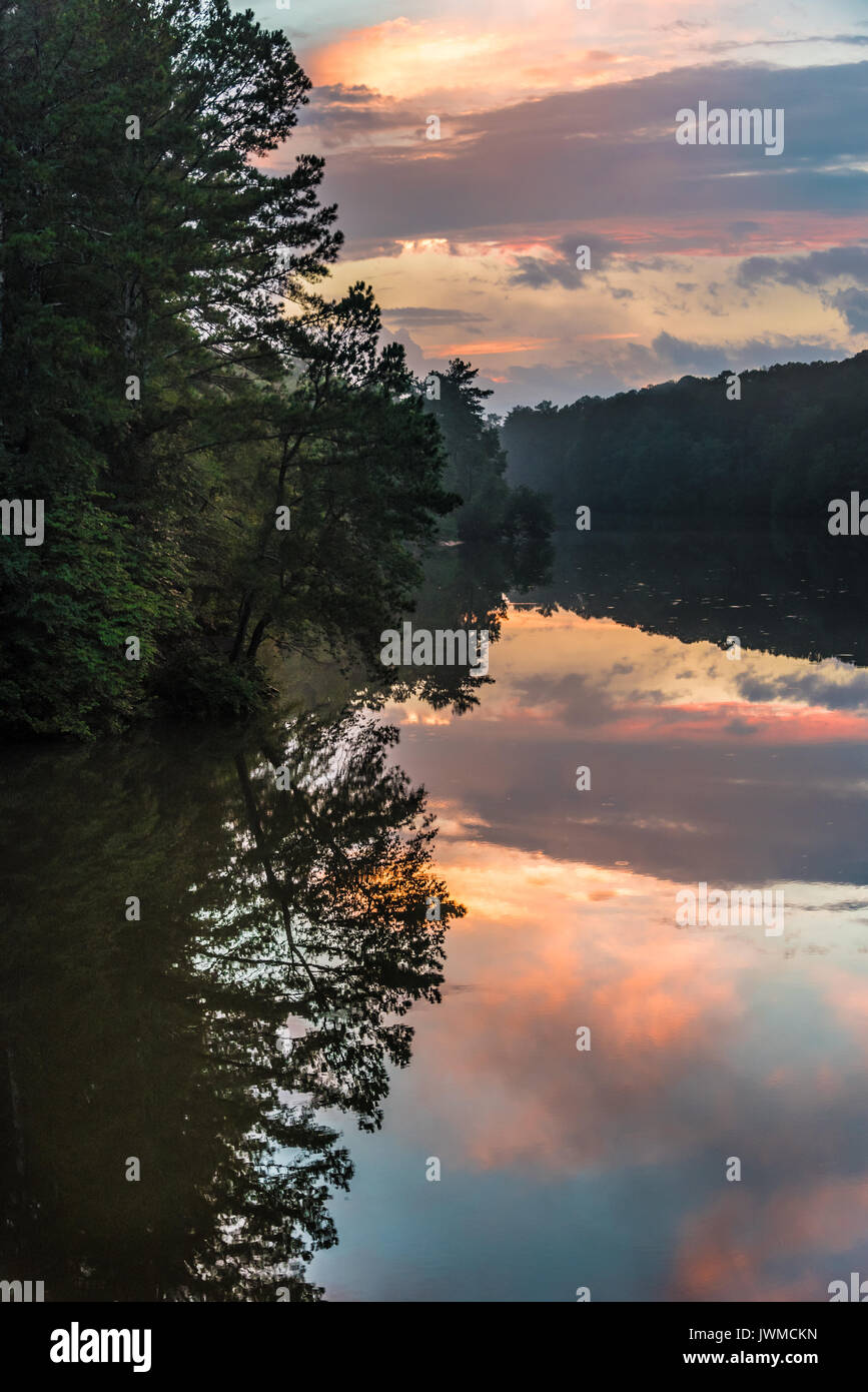 Ein farbenfroher Sonnenuntergang Himmel spiegelt sich in der immer noch Wasser von Stone Mountain Lake am Stone Mountain Park in Atlanta, Georgia, USA. Stockfoto