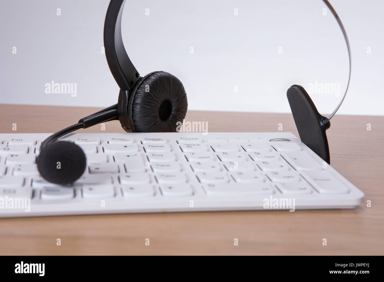 Computer Tastatur mit Headset und Mike auf einer hölzernen Schreibtisch in ein Konzept von einem Call Center, Client Services oder Telemarketing Stockfoto