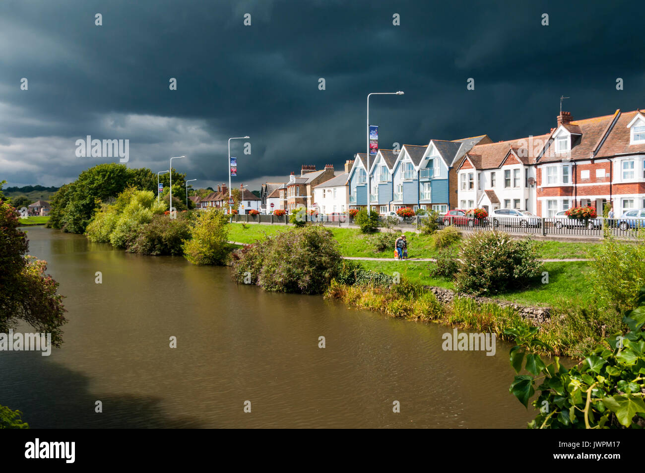 Sturmwolken über der Royal Military Canal und Häuser in Rampart Straße in Hythe, Kent. Stockfoto