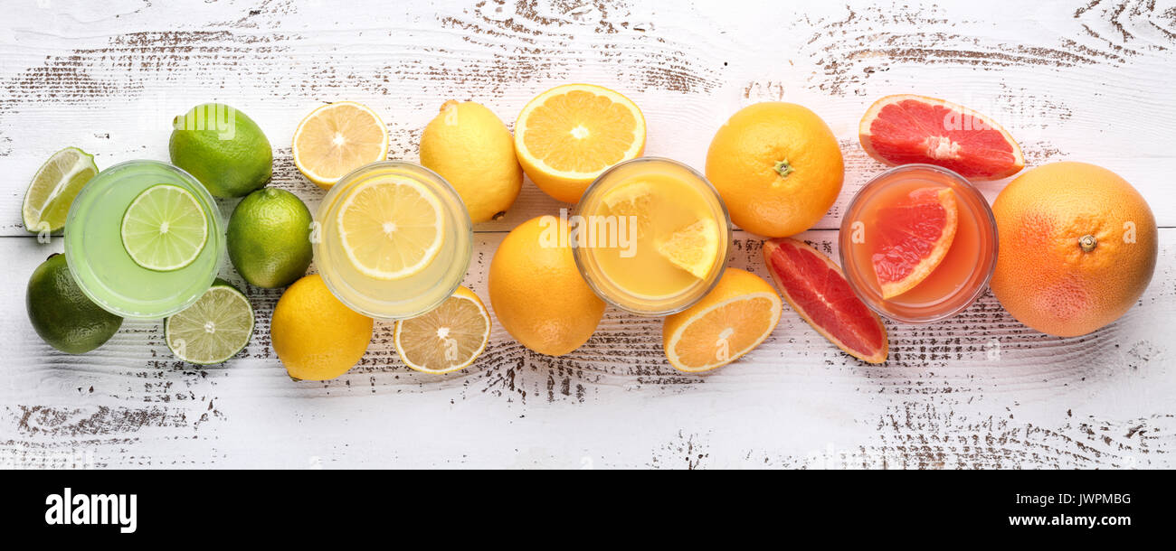 Glas Zitronensaft auf Holz- Hintergrund mit Schichten von Zitrusfrüchten Stockfoto