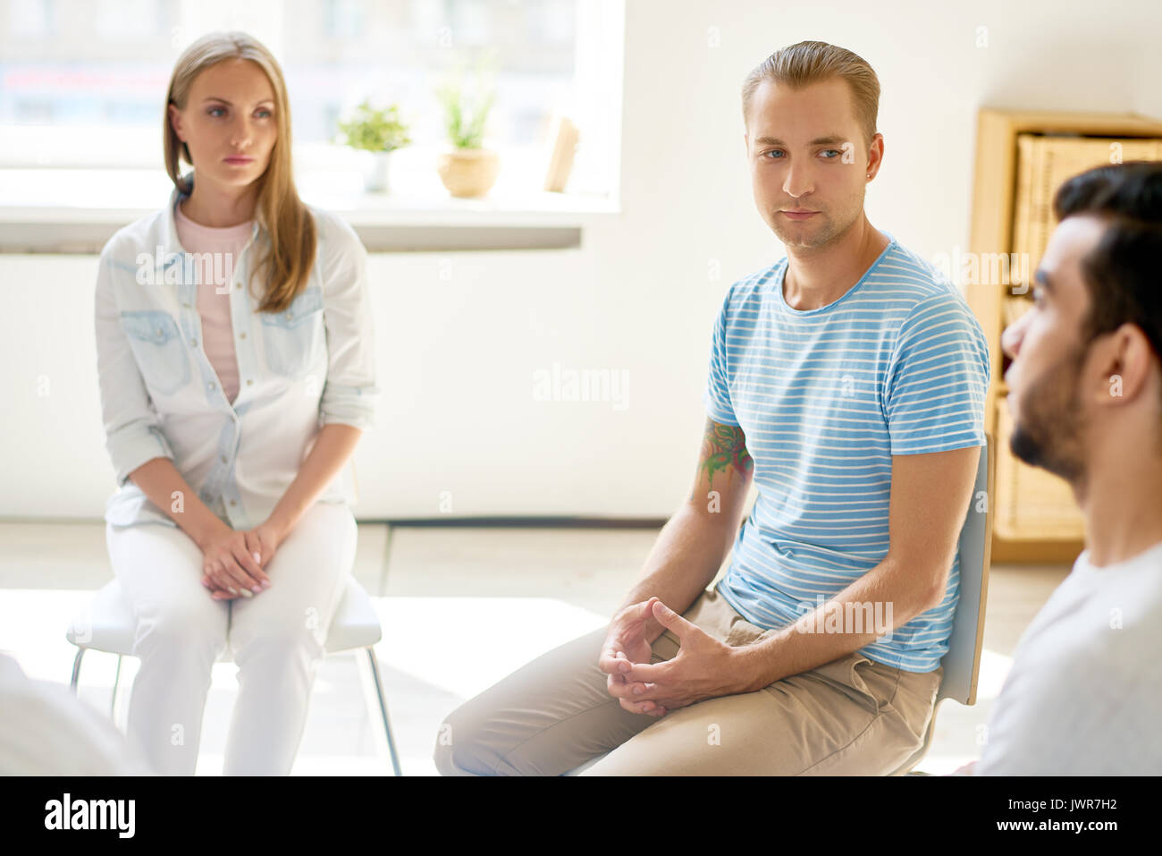 Portrait des modernen jungen Mann aufmerksam zuhören an andere Teilnehmer der Gruppe Sitzung sitzen im Kreis teilen Probleme Stockfoto