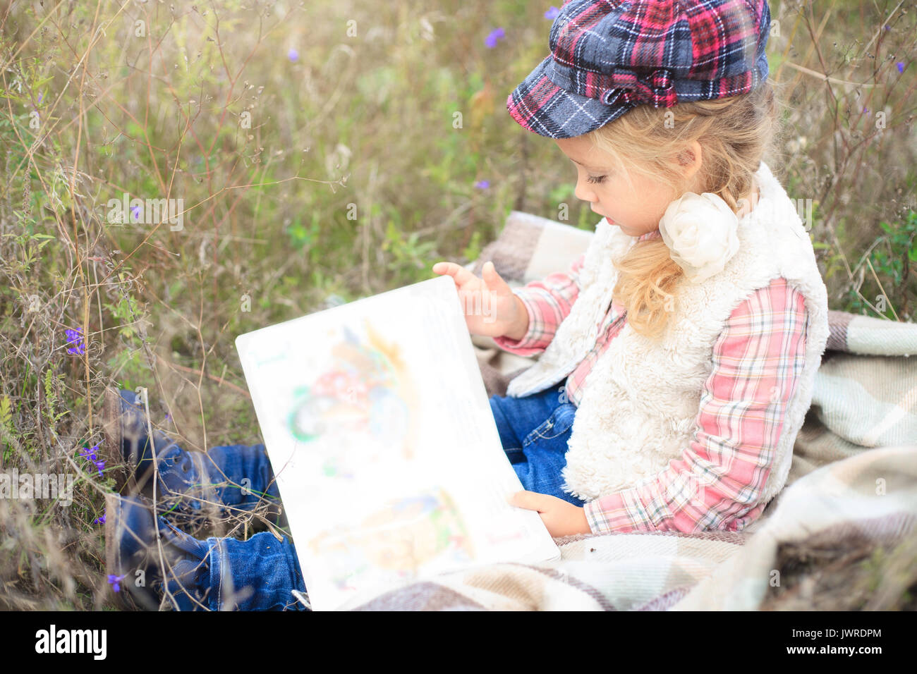 Kleine süsse kleine Mädchen ist ein Buch lesen in der Natur vor dem Hintergrund der Herbst Wiese. Stockfoto