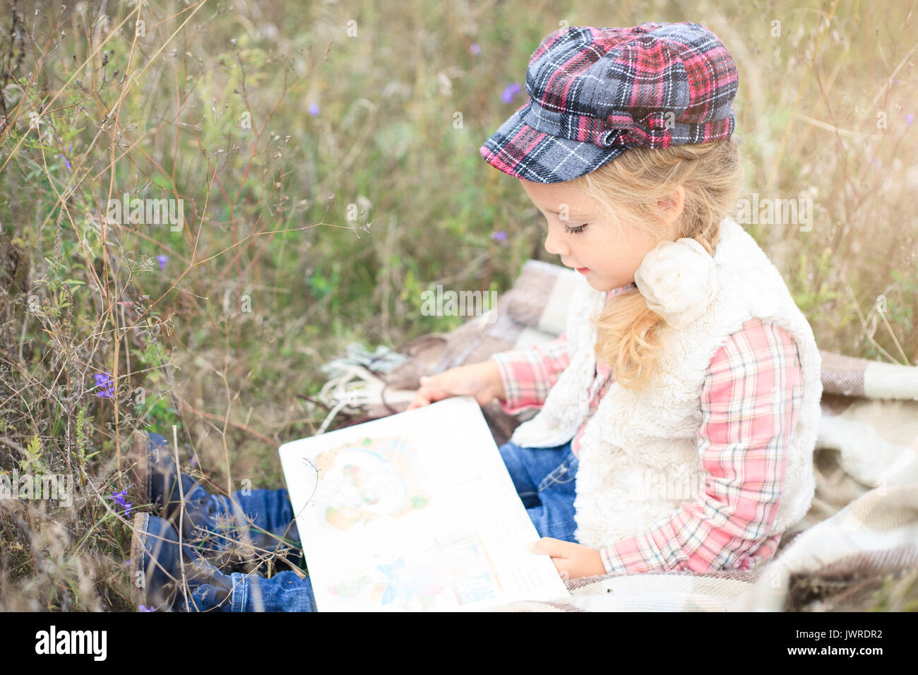 Kleine süsse kleine Mädchen ist ein Buch lesen in der Natur vor dem Hintergrund der Herbst Wiese. Stockfoto