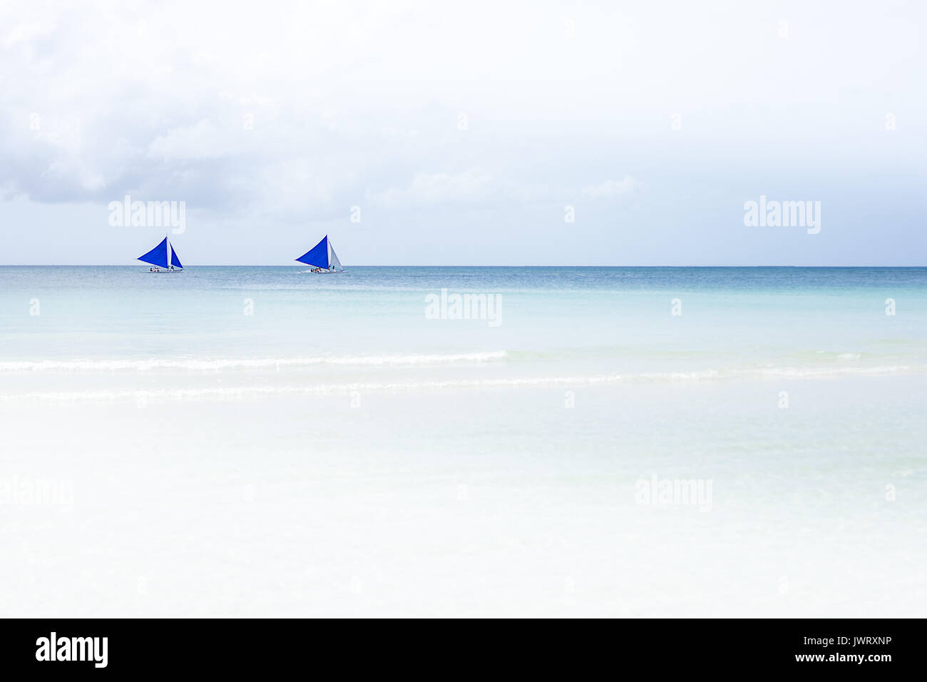 Einfache 2 blaue Segel Filipino Segelboote auf einem blauen Horizont des weißen Sand Strand von Boracay, Philippinen. Stockfoto
