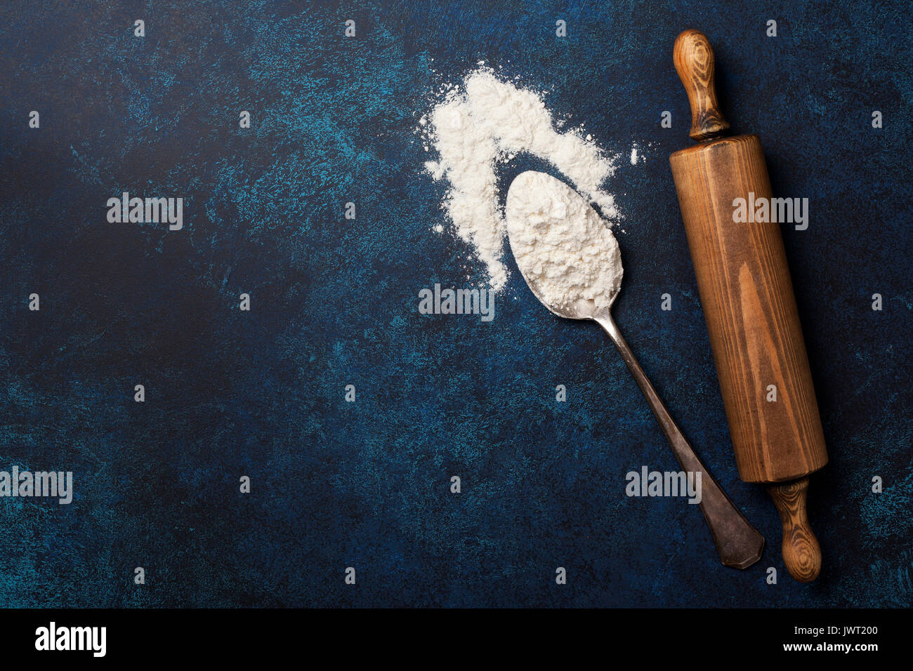 Alte Löffel mit Mehl, Rolling Pin auf blauem Hintergrund. Ansicht von oben, selektiver Fokus Stockfoto