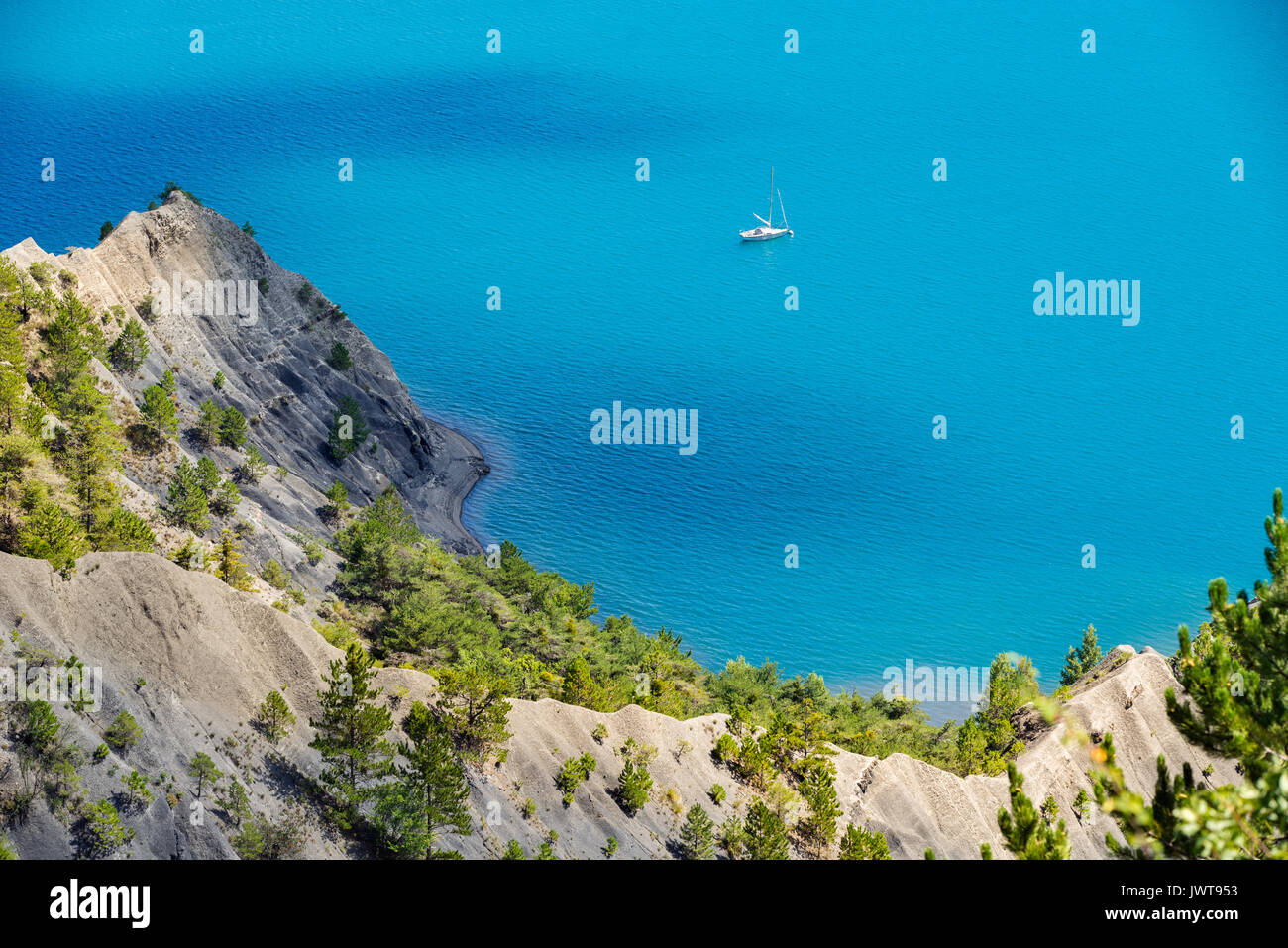 Serre-Poncon Lake im Sommer mit tiefblauen Wasser und Segelboot. Hautes-Alpes, Region PACA, Südliche französische Alpen, Frankreich Stockfoto
