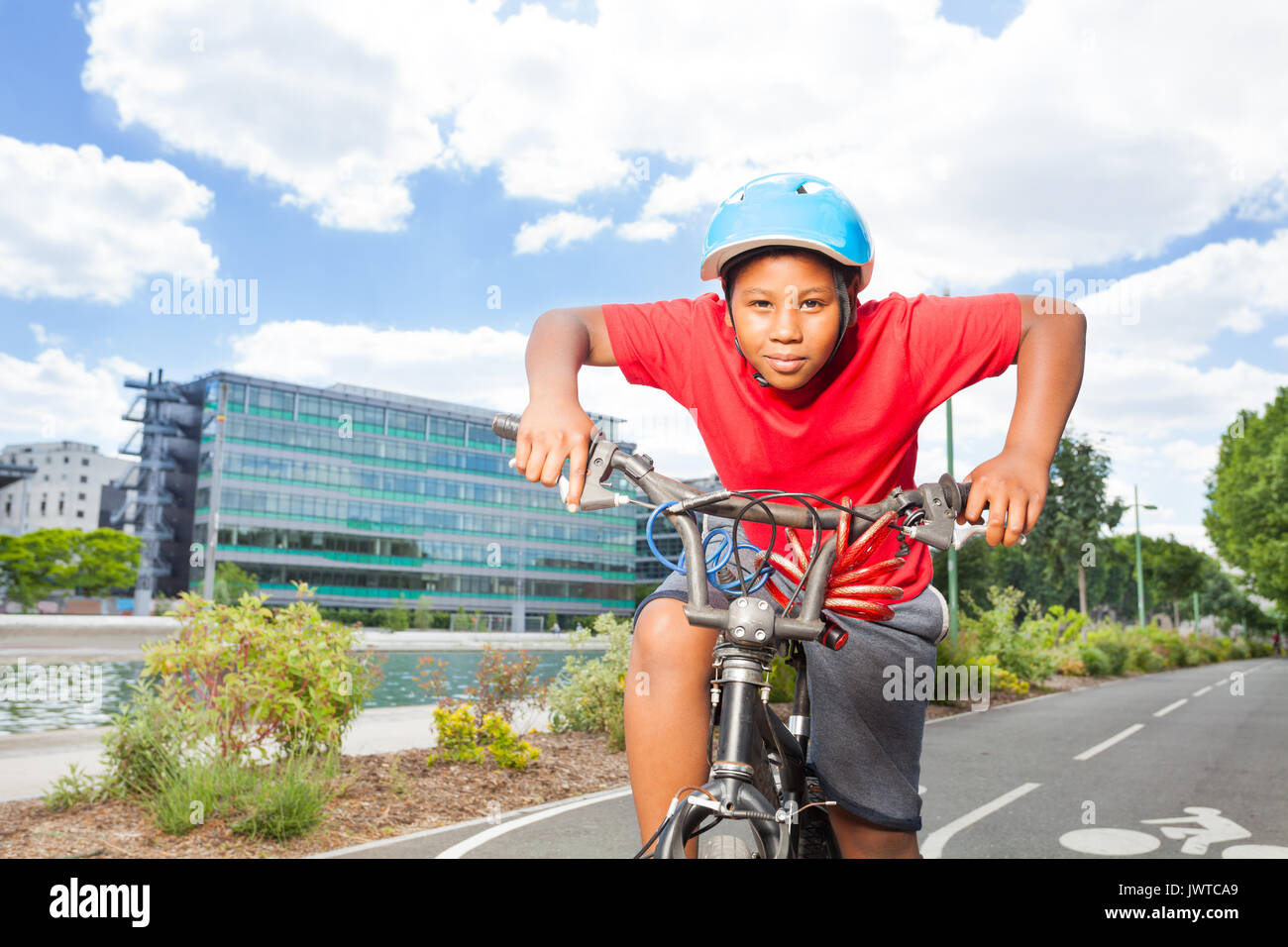 Portrait von Jugendlichen afrikanischen Jungen in Sicherheit Helm reiten sein Fahrrad auf Radweg im Sommer Stockfoto