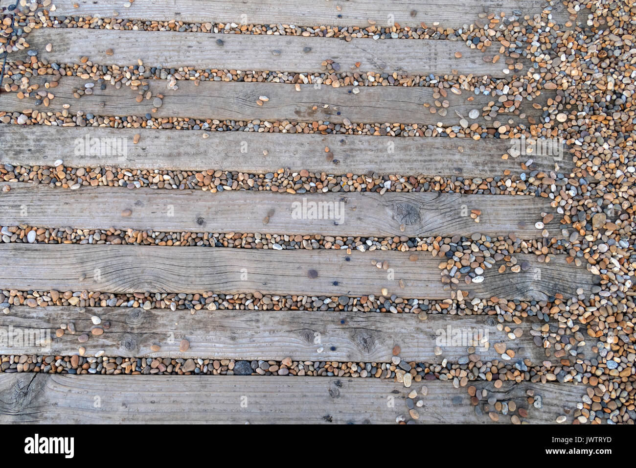 Rutschige Wanderweg aus Streifen aus Holz mit kleinen Steinchen gefüllt. Stockfoto