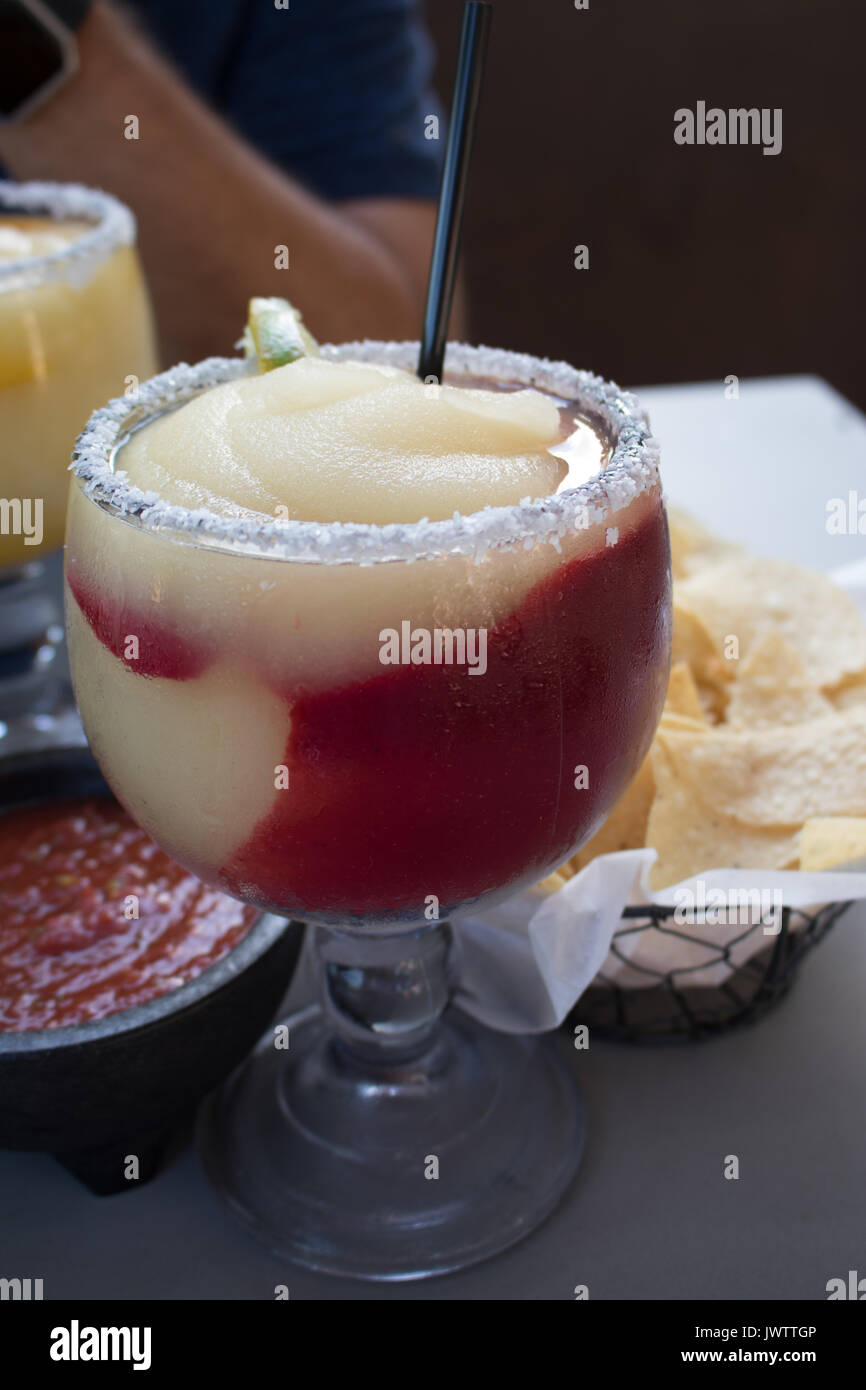 Frozen Margarita mit Raspberry Swirl, gesalzen Rim und Kalk Schicht. Chips und Salsa im Hintergrund. Stockfoto