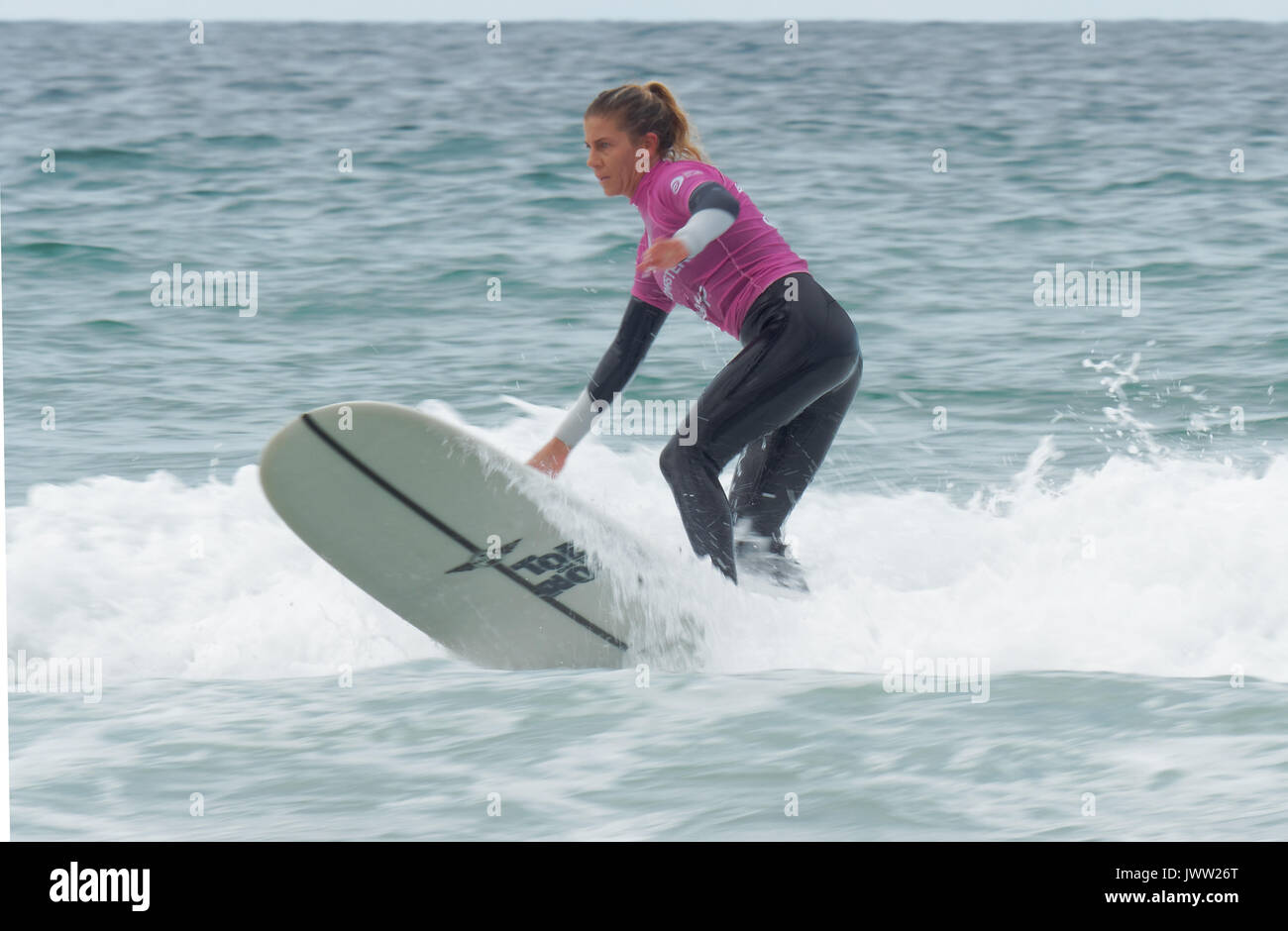 Surfen Brüder und weibliche Pro Surfer im Sonnenschein an Longboard contest Fistral Beach GROSSBRITANNIEN Stockfoto