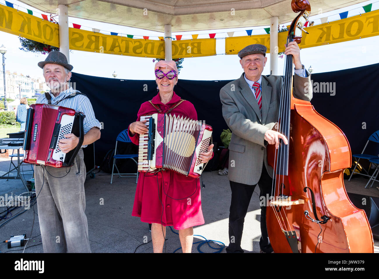 England, Broadstairs folk Woche. Folk Band, Stowfolk durchführen auf der Bühne beim Musikpavillon während der Hobby Horse Club zeigen hauptsächlich für Kinder. Close Up, zwei Akkordeonspieler und einem Cello player. Mit Blick auf und lächelte. Stockfoto