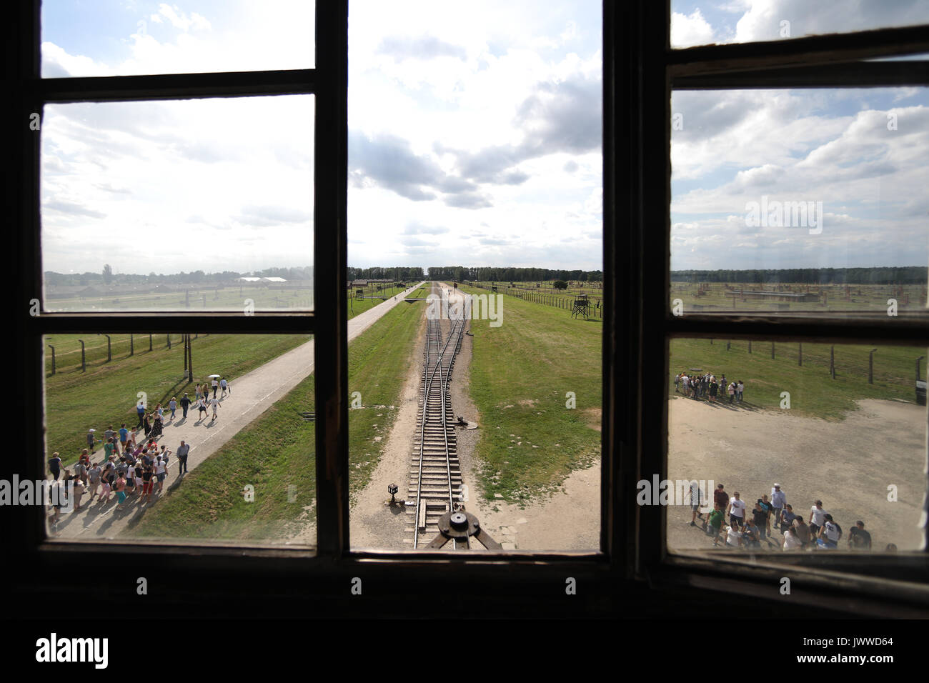 Die Besucher gehen über die ehemaligen Konzentrationslager Auschwitz-Birkenau in Oswiecim, Polen, 26. Juni 2017, durch ein Fenster des wachturms fotografiert. Die wichtigsten paramilitärischen Organisation im nationalsozialistischen Deutschland, SS (Schutzstaffel, lit. "Schutz Squadron"), lief die Konzentrations- und Vernichtungslager zwischen 1940 und 1945. Eingehende Deportierten wurden in verschiedene Gruppen, die auf der Rampe zwischen den Tracks ausgewählt, nachdem Sie in Birkenau angekommen. Die Menschen, die nicht in der Lage waren zu arbeiten (ältere Menschen, Menschen mit schwachen, Frauen, Kinder) waren manchmal zu den Gaskammern direkt ohne Registrierung gesendet. Etwa 1.1 bis Stockfoto