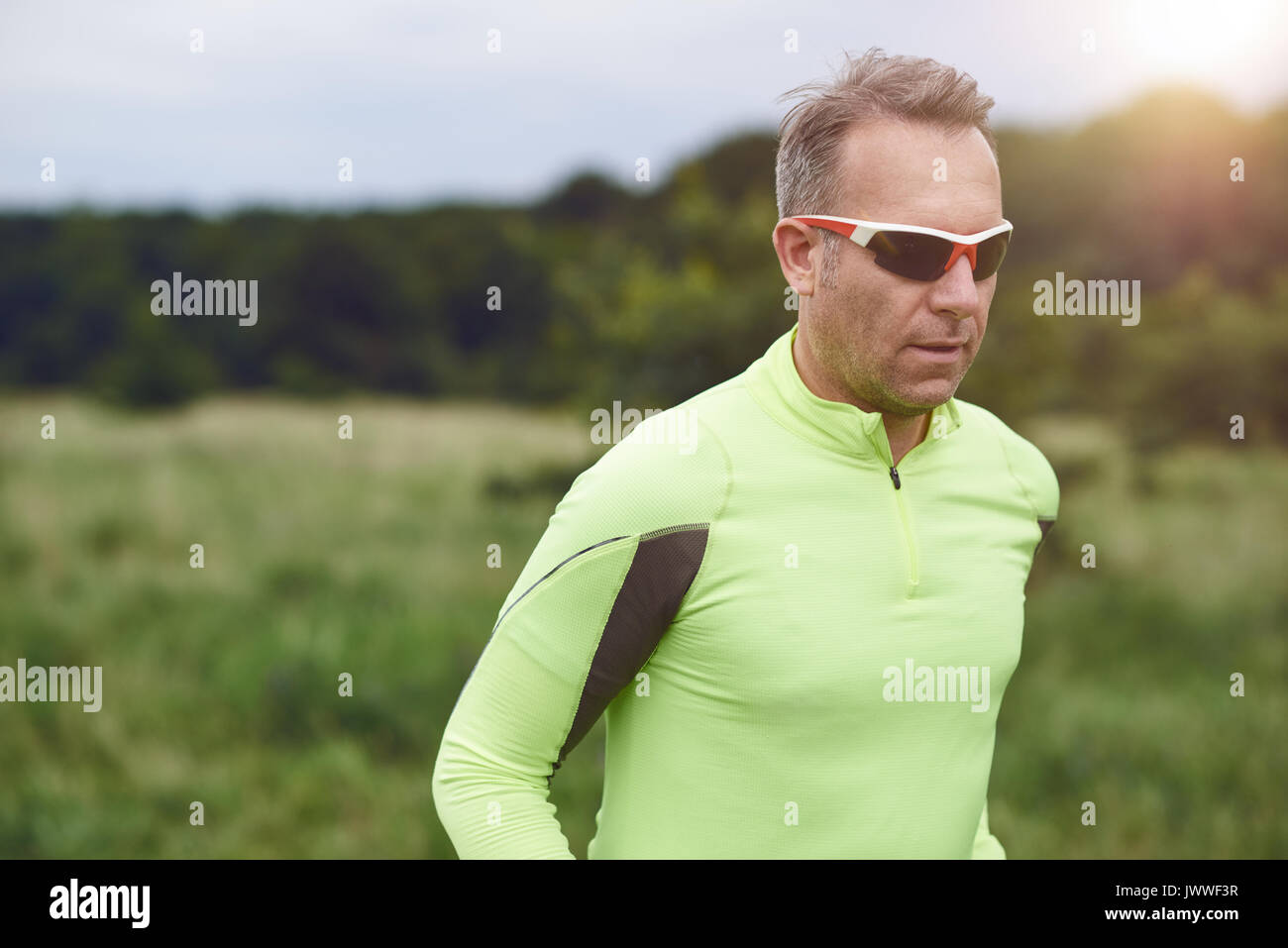 Im mittleren Alter sportlich Mann mit Sonnenbrille Joggen in der Natur aber Grünland in Nahaufnahme Oberkörper mit Kopie Raum Stockfoto