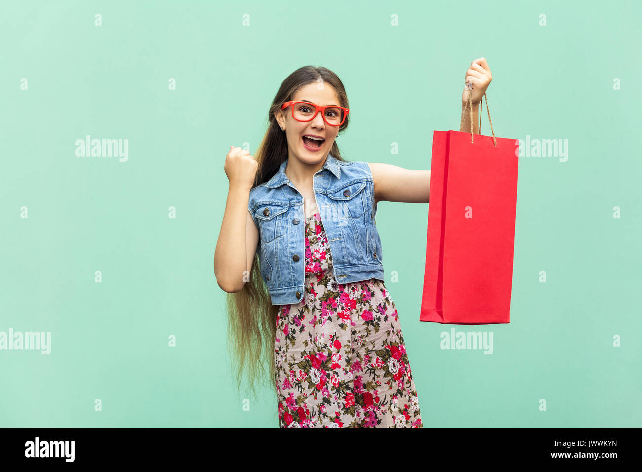 Die schöne langhaarige Mädchen in Freizeitkleidung mit Einkaufstaschen, an der Kamera suchen, feiert den Sieg. Kaukasische blondie Modell. Verkauf, Shop, Stockfoto