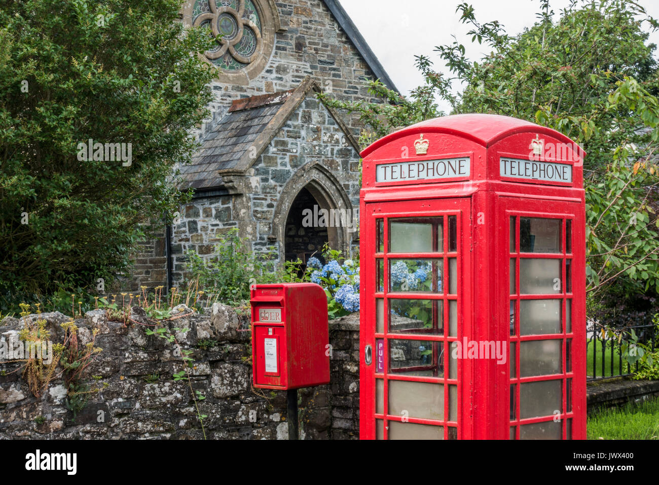 Ein traditionelles rotes Royal Mail Briefkasten neben einem Ikonischen rotes Telefon Kiosk, außerhalb der alten Kirche, Lydford, in der Nähe von Okehampton, Devon, England, UK. Stockfoto