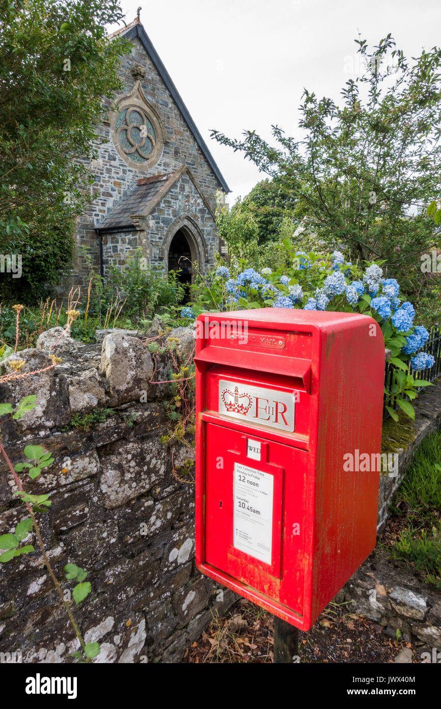 Ein traditionelles rotes Royal Mail Briefkasten vor der alten Kirche, in der Nähe von Okehampton Lydford, Devon, England, UK. Stockfoto