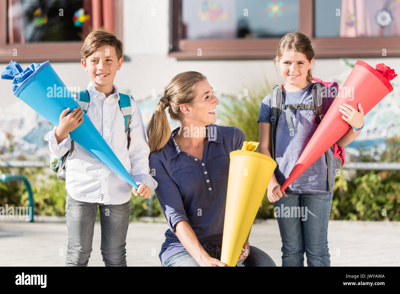 Mutter und Kinder am ersten Tag der Schule mit Süßigkeiten Kegel Stockfoto