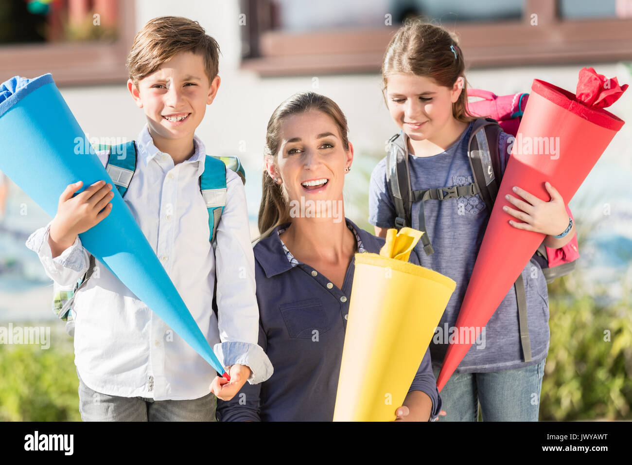 Mutter und Kinder am ersten Tag der Schule mit Süßigkeiten Kegel Stockfoto