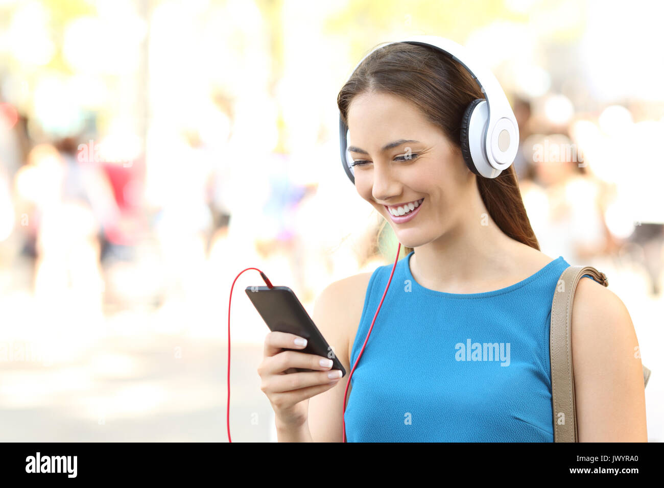 Porträt eines Mädchens Musik hören, Kopfhörer tragen und gehen auf die Straße Stockfoto