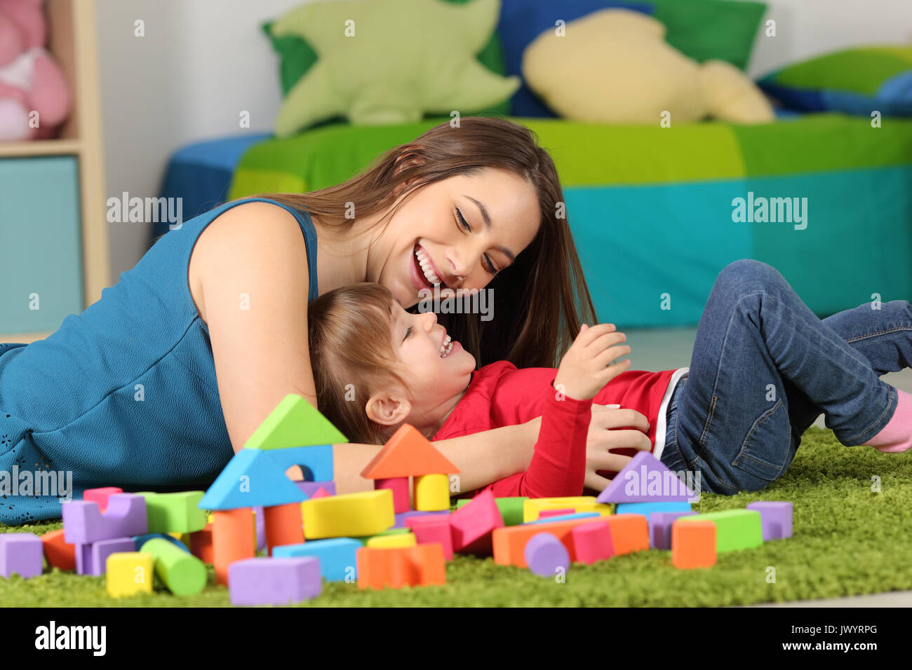 Mutter oder Kindermädchen spielen mit einem Kind auf dem Teppich in einem Zimmer zu Hause Stockfoto