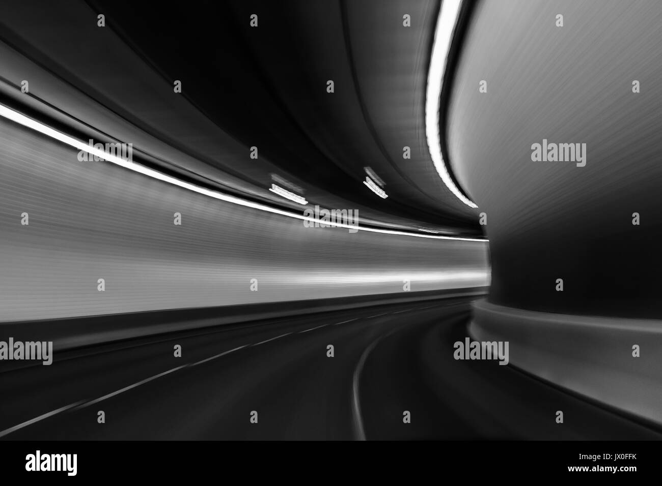 Blick auf die hell beleuchteten Tunnel von einem schnell fahrenden Auto; leichte Unschärfe übertreibt die Bewegung; Schwarz und Weiß Stockfoto