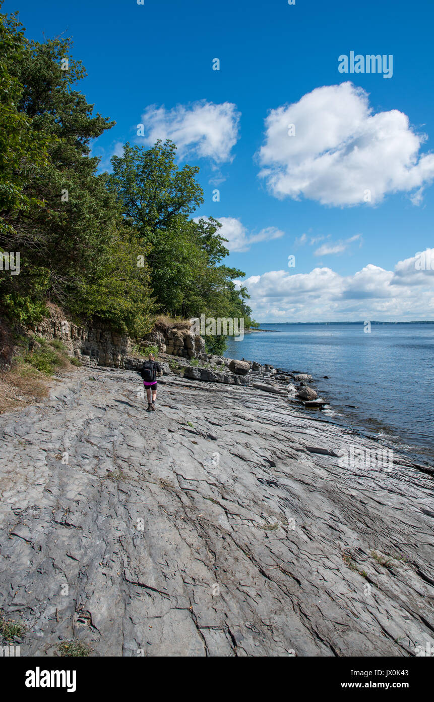 Frau auf einem felsigen Ufer des Lake Champlain gehen und mit Blick auf den See Stockfoto