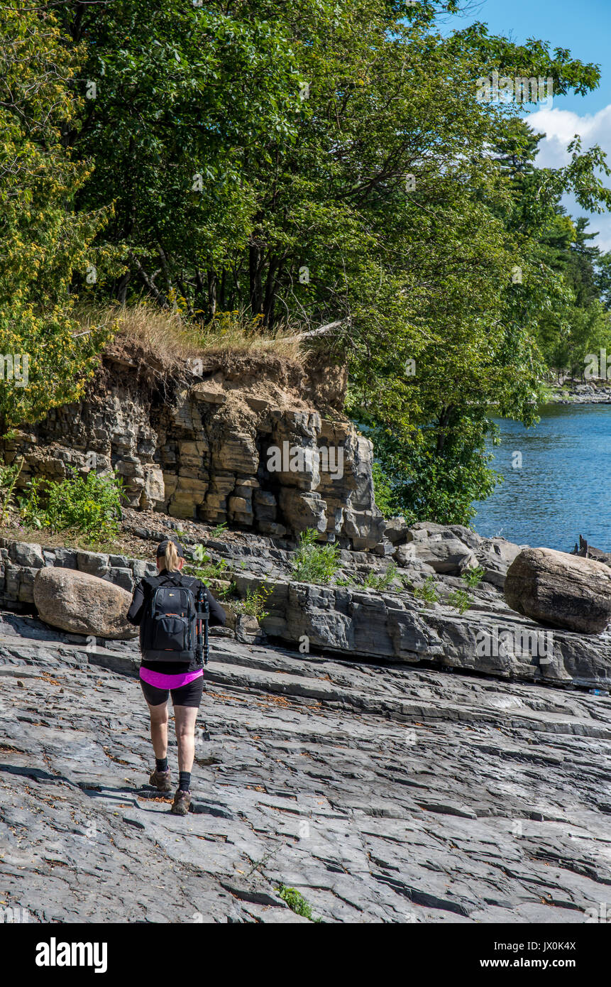 Frau auf einem felsigen Ufer des Lake Champlain gehen und mit Blick auf den See Stockfoto