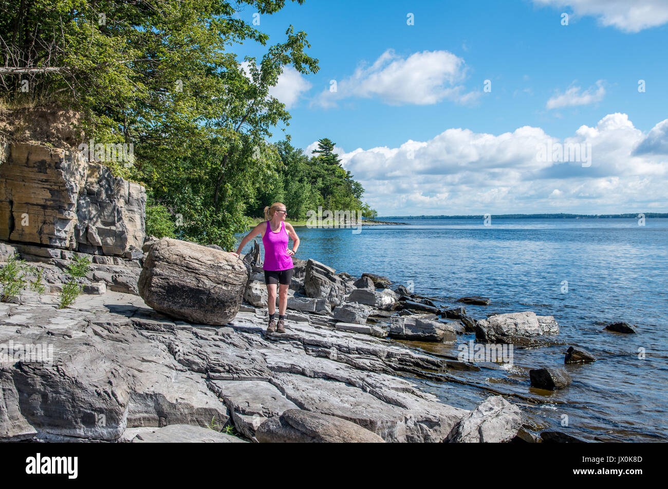 Frau auf einem felsigen Ufer des Lake Champlain gehen und mit Blick auf den See Stockfoto