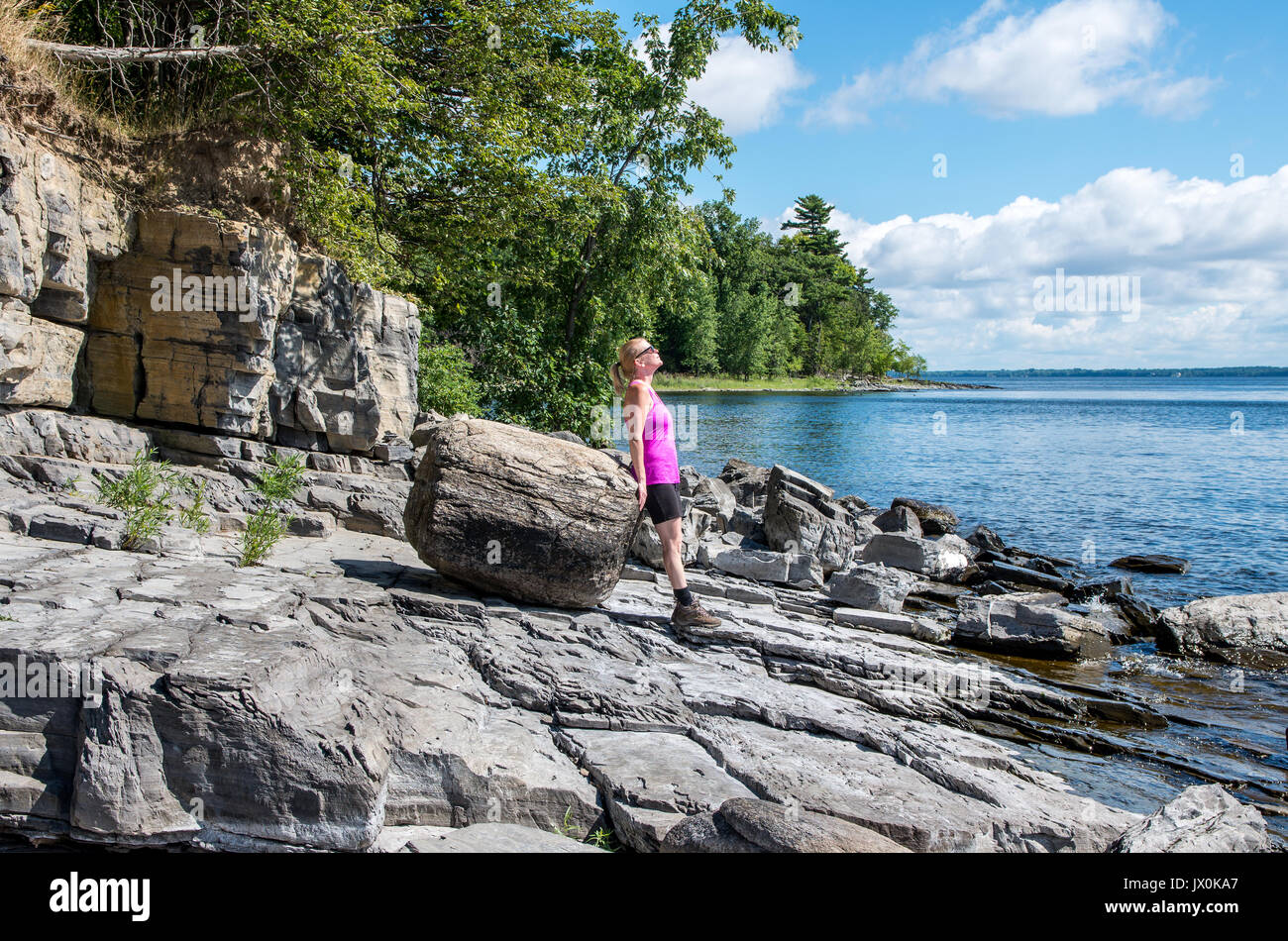 Frau auf einem felsigen Ufer des Lake Champlain gehen und mit Blick auf den See Stockfoto